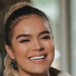 Portrait of Karol G smiling, with her hair in a long braid