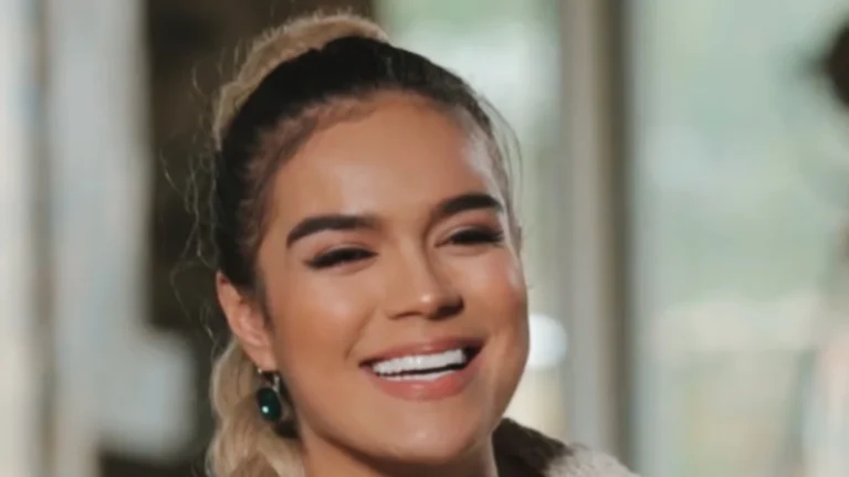 Portrait of Karol G smiling, with her hair in a long braid